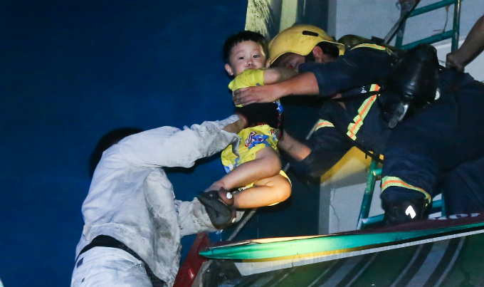 A woman and a little boy are taken out of the building on a fire truck lift. Photo by Quynh Tran