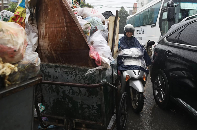 A motorbike driver rides next to garbage trolleys in Nam Tu Liem District, Hanoi. Photo by VnExpress.